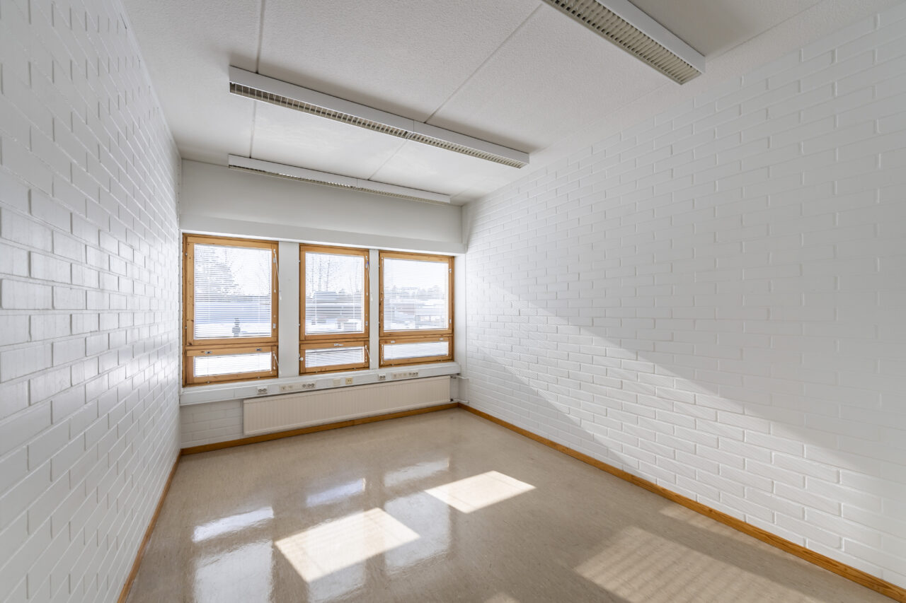Yksi kiinteistön (Toritalo) työhuoneista. Huoneen päässä on kolme ikkunaa, joista paistaa aurinko. Vaaleanruskea kiillotettu lattia. Valkoiset tiiliseinät. Katossa valaisimia. Huoneen koko on yli 10 neliömetriä.